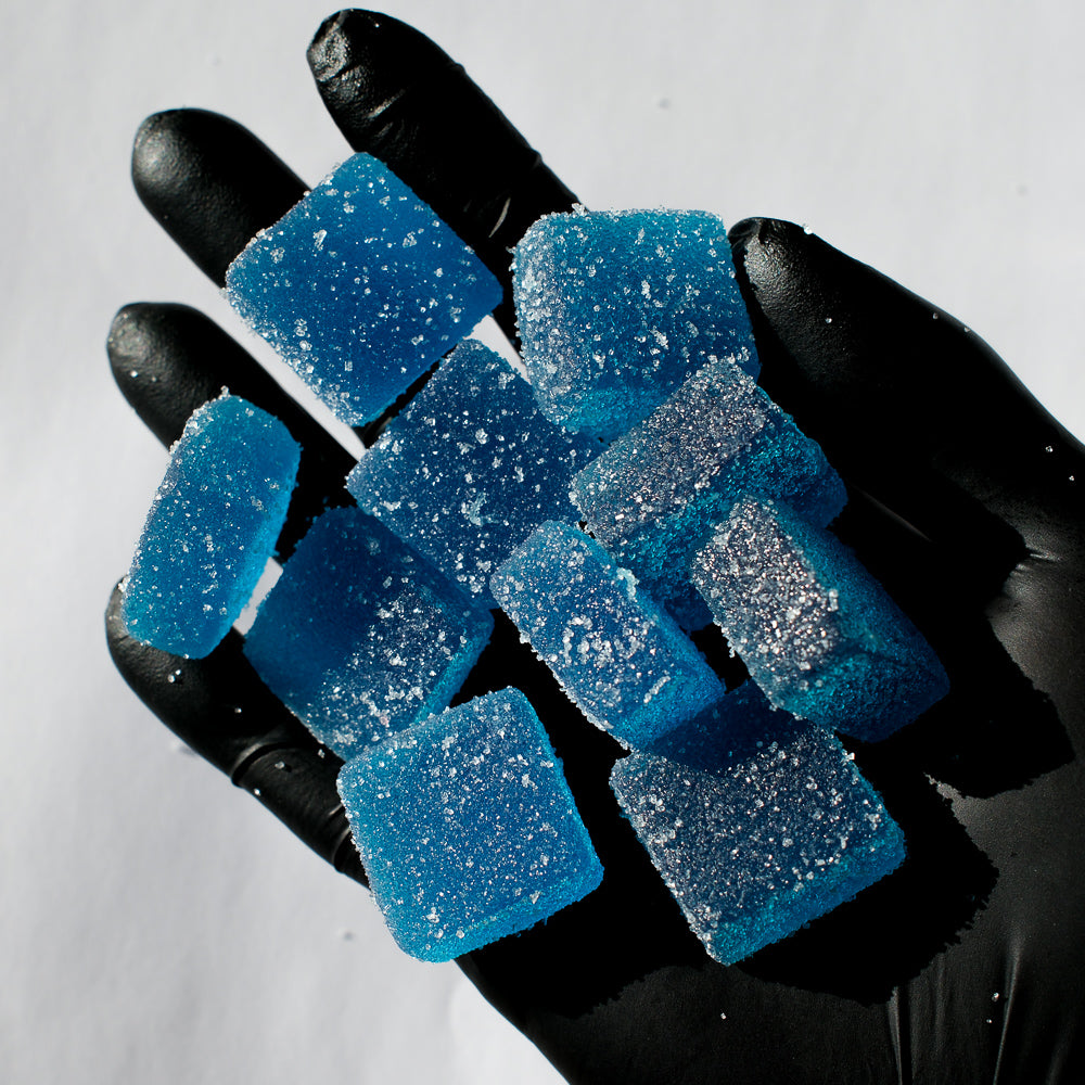 Tas de de gummies au THC bleus dans une main